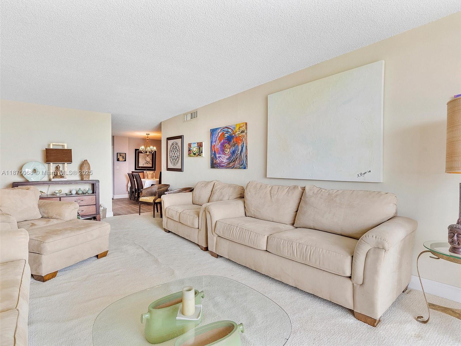 A living room features beige sofas, a glass coffee table, and wall art — 1470 NE 125th Ter, North Miami FL 33161, NORTH MIAMI, FL
