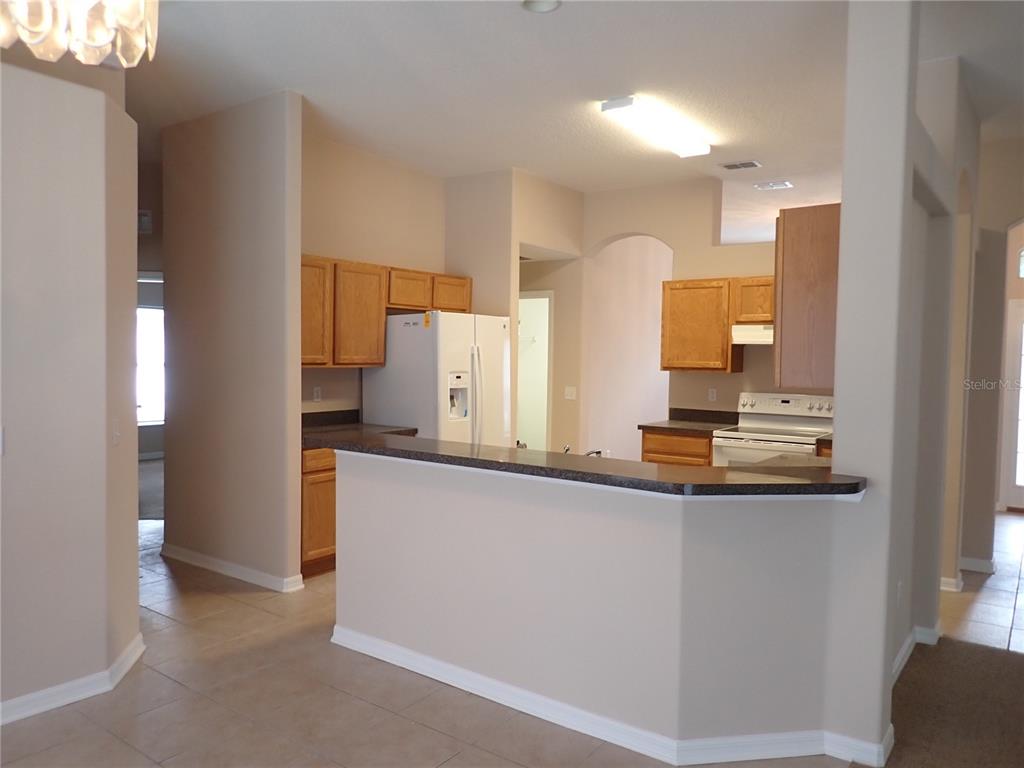 A kitchen features light-colored walls, wood cabinets, dark countertops, and a breakfast bar — 132 BERKSHIRE LANE, PALM COAST, FL