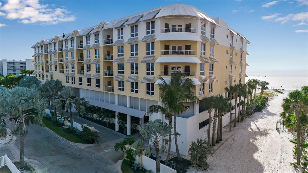 An exterior view of a multi-story beachfront apartment building with palm trees and sandy dunes — 915 SEASIDE DRIVE UNIT 412, SARASOTA, FL