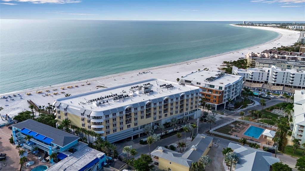 An aerial view shows a multi-story hotel building situated along a sandy beach and ocean — 915 SEASIDE DRIVE UNIT 412, SARASOTA, FL