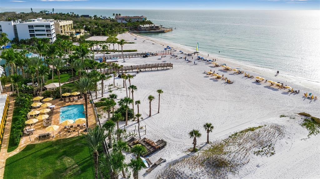 An aerial view of a white sand beach with a pool, palm trees, and ocean — 915 SEASIDE DRIVE UNIT 412, SARASOTA, FL
