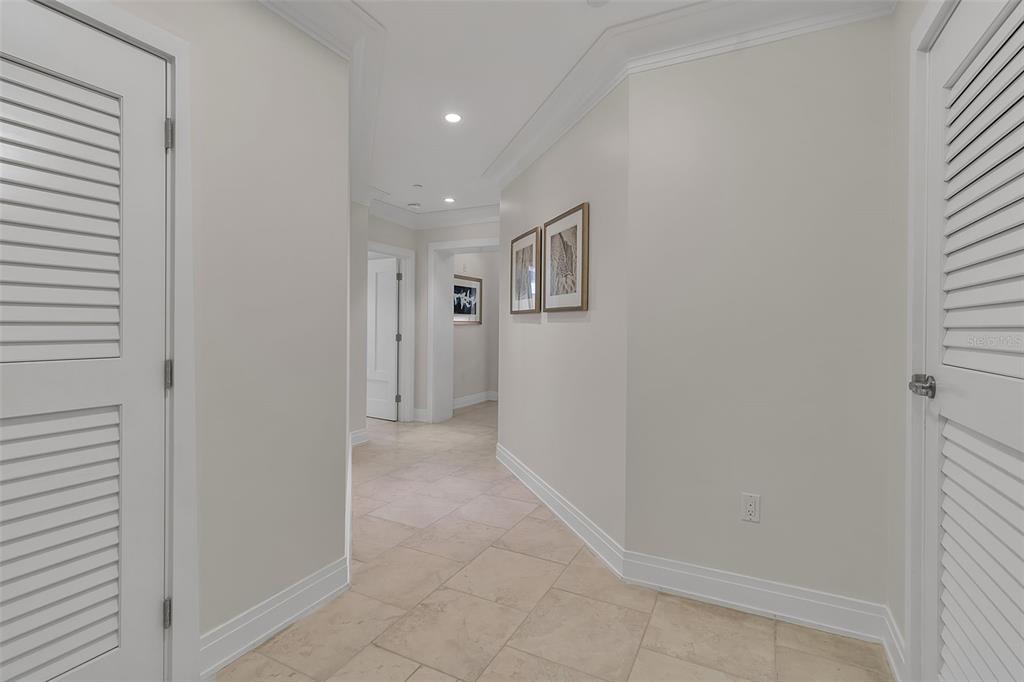 A hallway with light tile flooring, white walls, and louvered doors on both sides — 915 SEASIDE DRIVE UNIT 412, SARASOTA, FL