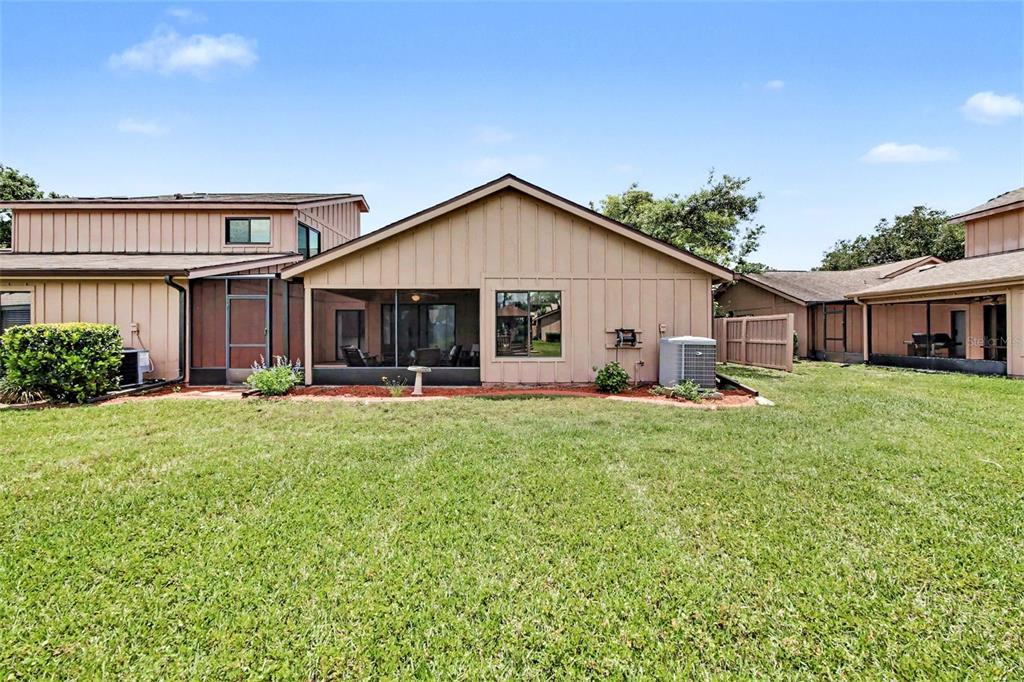 The exterior view shows a tan house with a screened-in porch and a grassy backyard — 1914 SPRUCEWOOD WAY, PORT ORANGE, FL