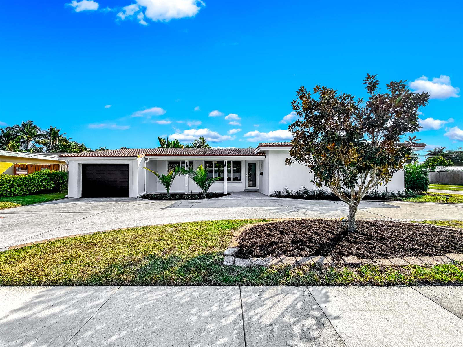 A white single-story house with a black garage door and a large front yard tree — 1098 W Camino Real, Boca Raton FL 33486, BOCA RATON, FL
