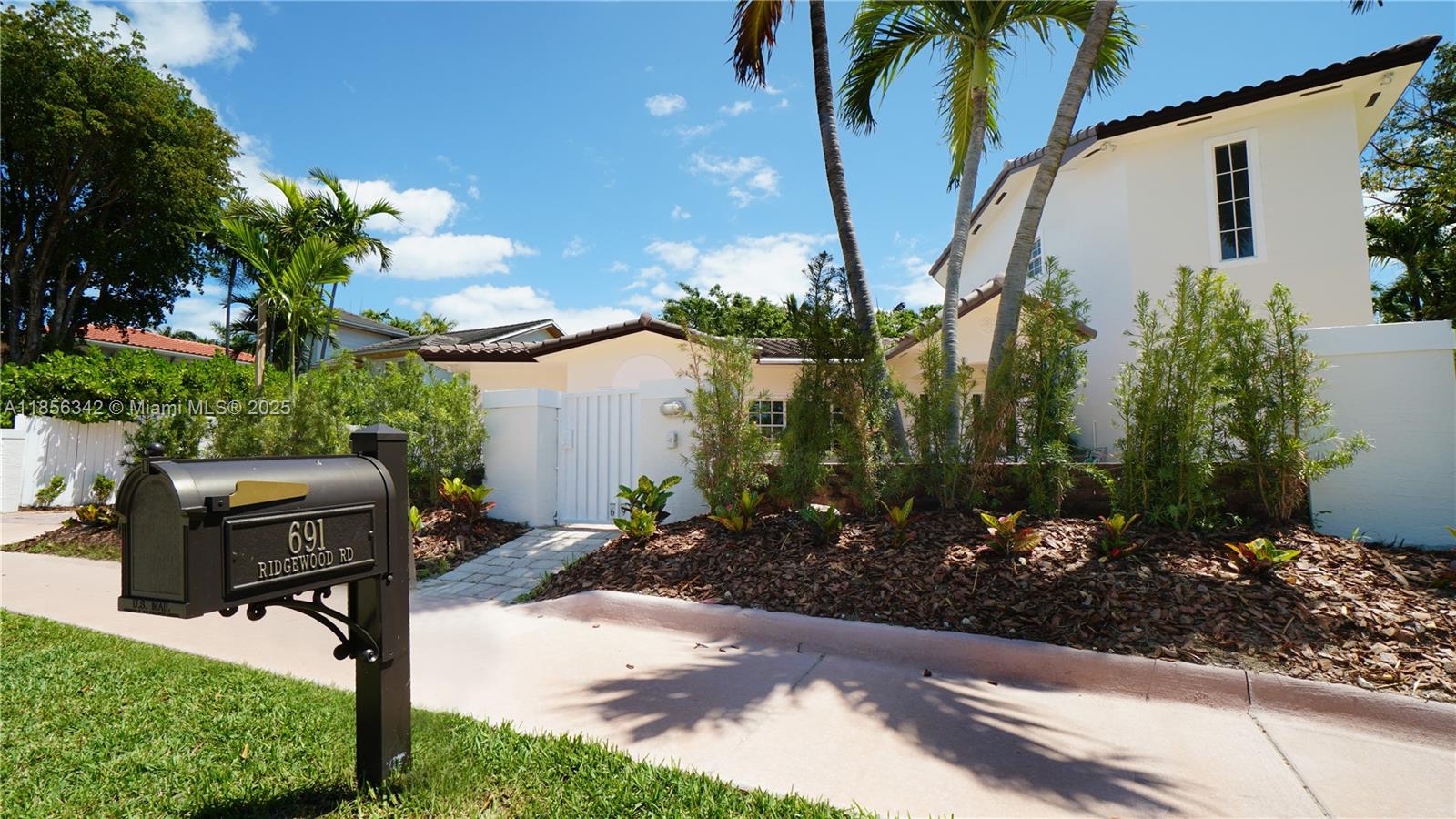 A mailbox stands in the foreground of a white house with palm trees and landscaping — 691 Ridgewood Rd, Key Biscayne FL 33149, KEY BISCAYNE, FL