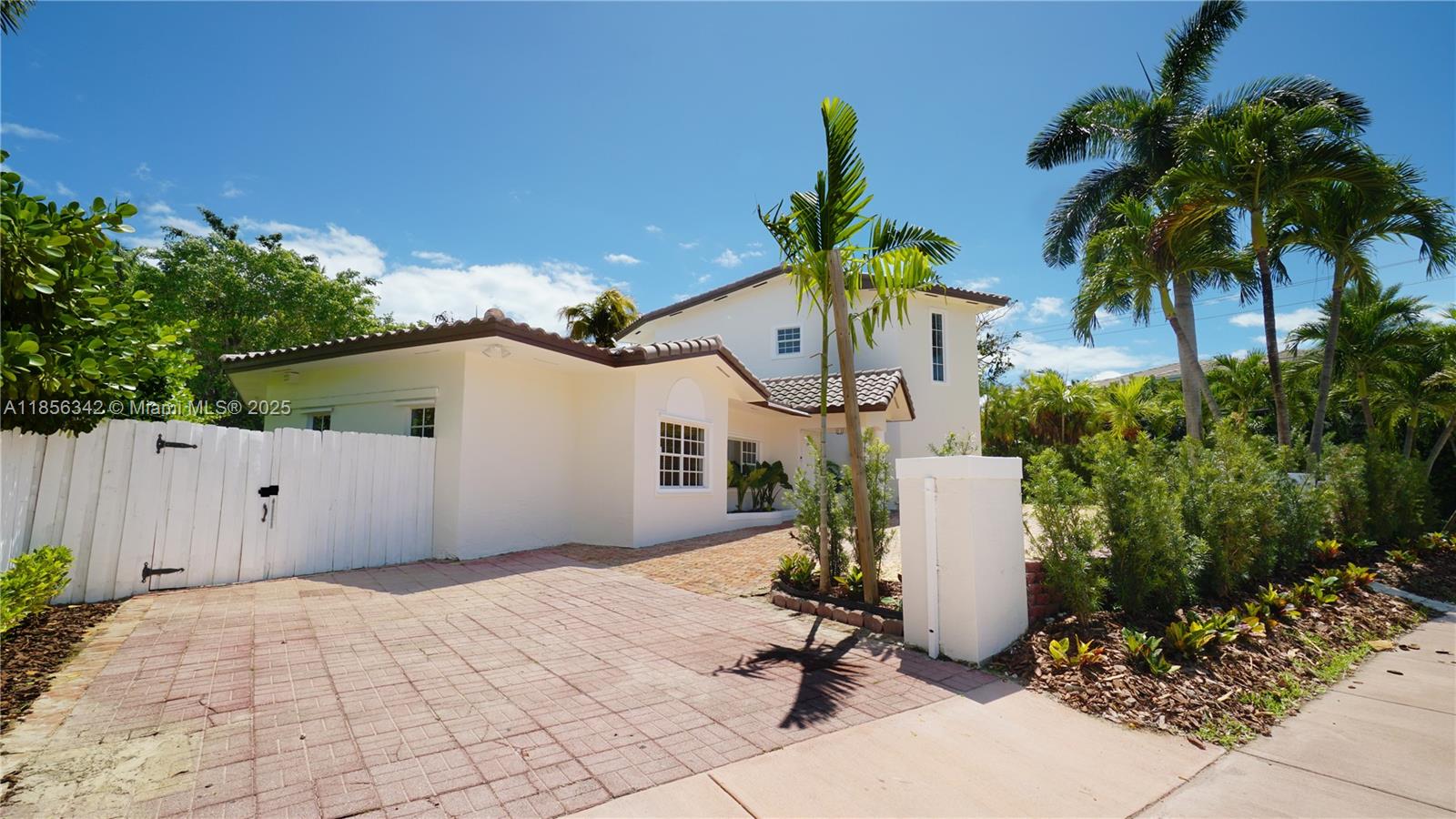 A two-story white house with a tiled roof and a paved driveway behind a fence — 691 Ridgewood Rd, Key Biscayne FL 33149, KEY BISCAYNE, FL