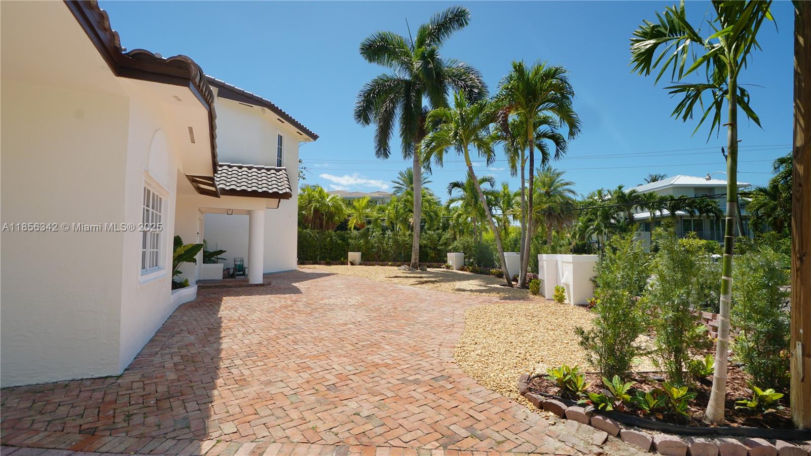 A brick-paved driveway leads to a white house surrounded by palm trees and landscaping — 691 Ridgewood Rd, Key Biscayne FL 33149, KEY BISCAYNE, FL