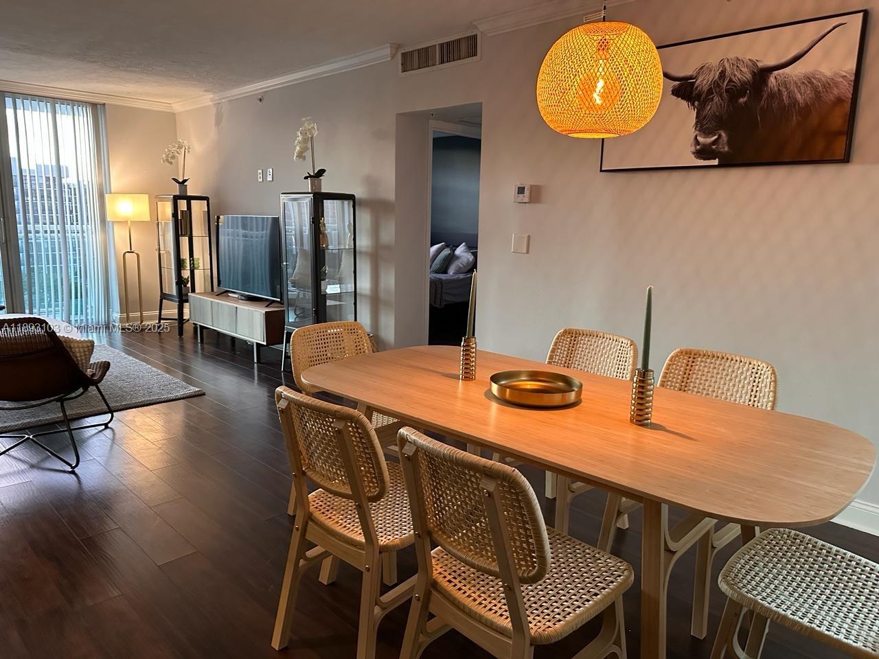 A dining area with a wooden table and woven chairs sits before a living room — 3000 S Ocean Dr # 612, Hollywood FL 33019, HOLLYWOOD, FL