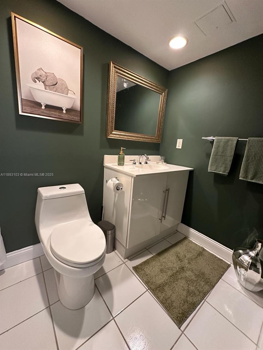 A bathroom features dark green walls, a white vanity, a toilet, and a framed elephant print — 3000 S Ocean Dr # 612, Hollywood FL 33019, HOLLYWOOD, FL