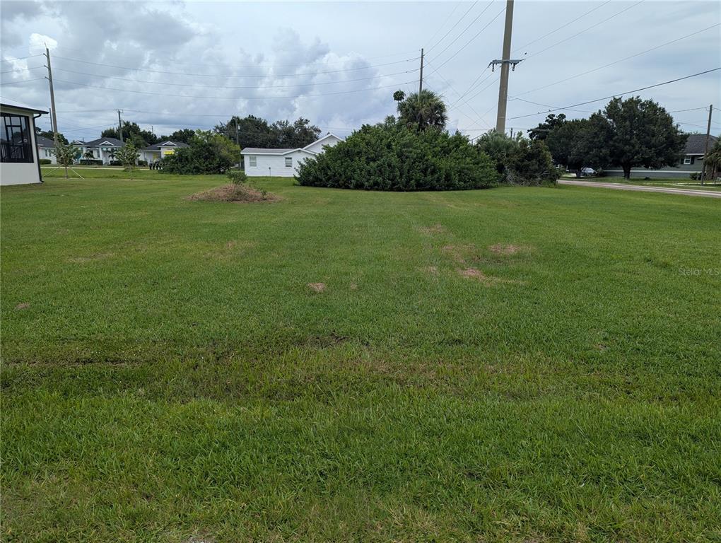A wide, grassy vacant lot features a large bush and utility poles under a cloudy sky — 340 SAN MARIE DRIVE, PUNTA GORDA, FL