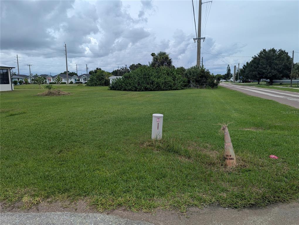 A vacant grassy lot features a utility pedestal and a traffic cone near a paved road — 340 SAN MARIE DRIVE, PUNTA GORDA, FL