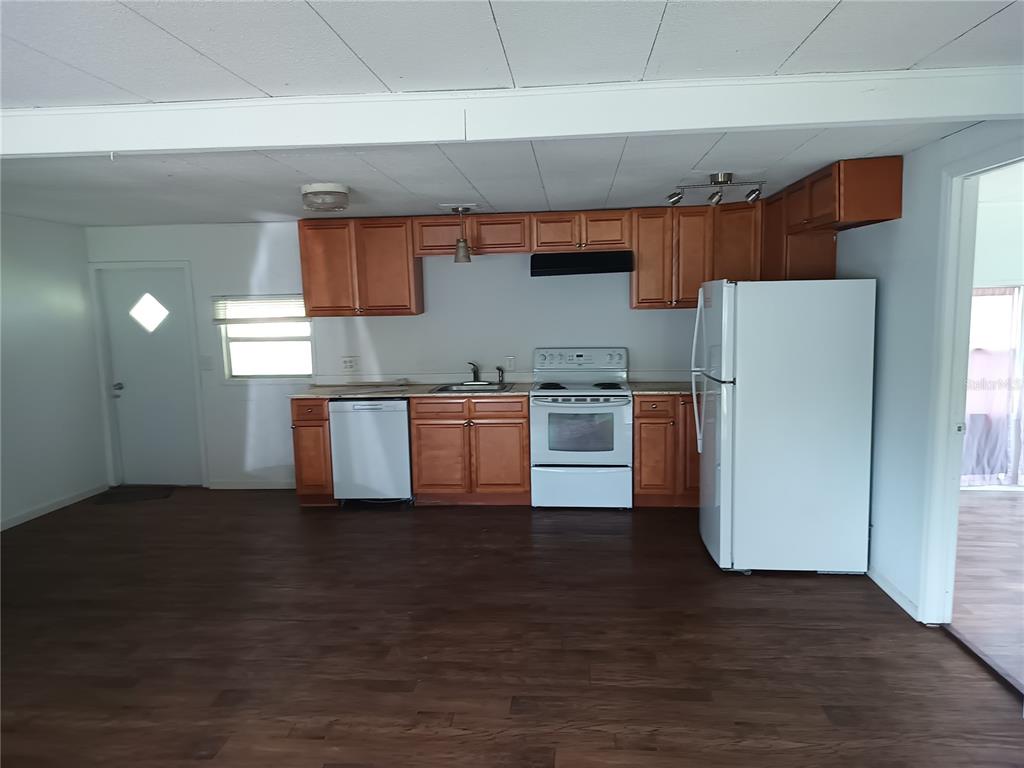 A kitchen featuring wood cabinets, white appliances, and dark wood-look flooring in an open space — 3368 MAPLE LANE, HAINES CITY, FL