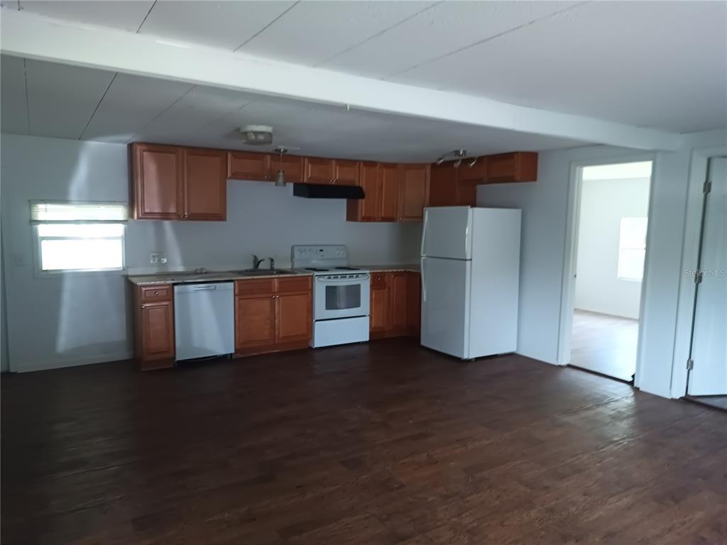 A kitchen with wood cabinets, white appliances, and dark wood-look flooring — 3368 MAPLE LANE, HAINES CITY, FL
