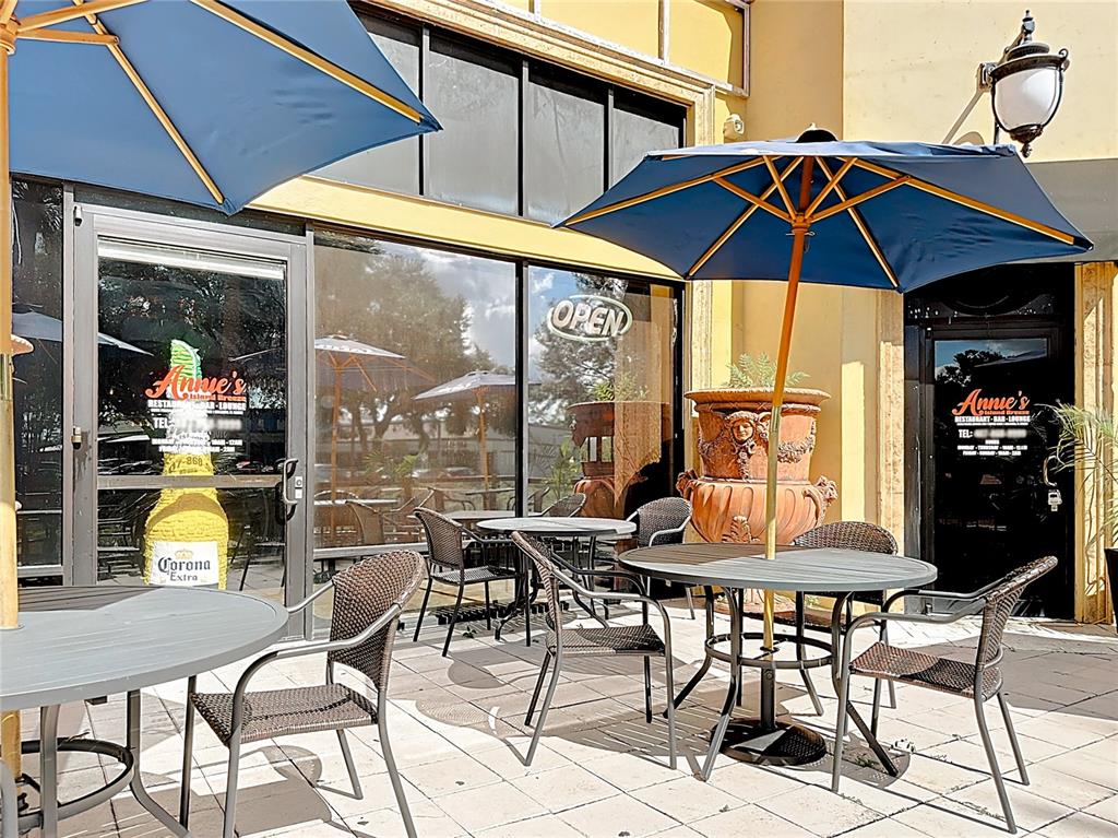 An outdoor patio features several round tables with blue umbrellas and wicker chairs — 6996 PIAZZA GRANDE AVENUE UNIT 100, ORLANDO, FL