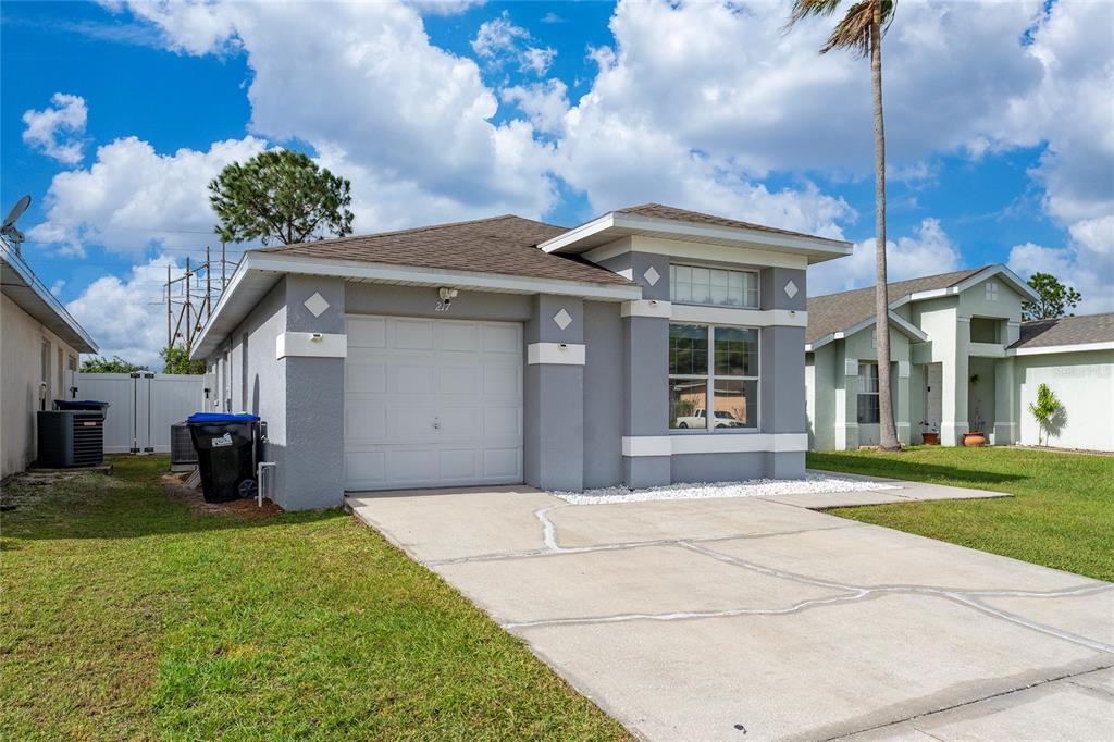 A gray single-story house features a one-car garage, a concrete driveway, and a front window — 217 WOODBAY COURT, ORLANDO, FL