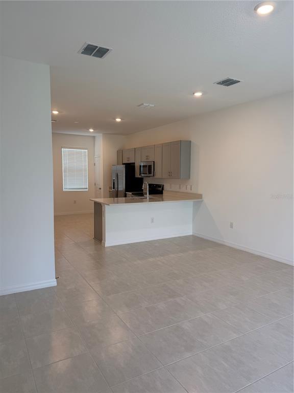 A kitchen with light gray cabinets and a breakfast bar overlooks an open living area — 2882 SKYLINE LOOP, KISSIMMEE, FL