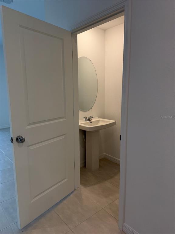 A doorway opens into a small bathroom featuring a pedestal sink and an oval mirror — 2882 SKYLINE LOOP, KISSIMMEE, FL