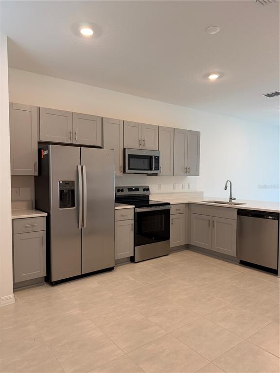 A kitchen with light gray cabinets, stainless steel appliances, and light-colored tile flooring — 2882 SKYLINE LOOP, KISSIMMEE, FL