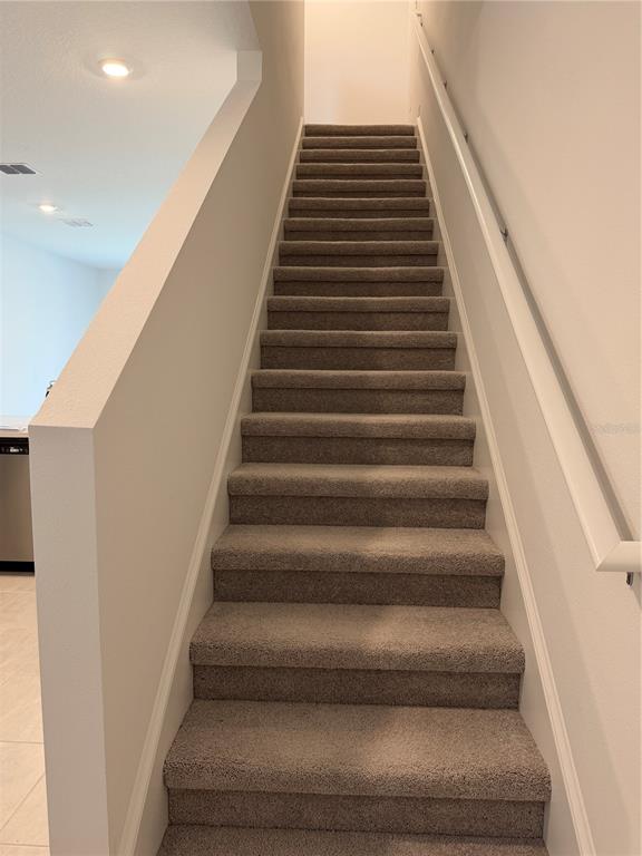 A straight staircase with gray carpeted steps and a white handrail leads upward — 2882 SKYLINE LOOP, KISSIMMEE, FL