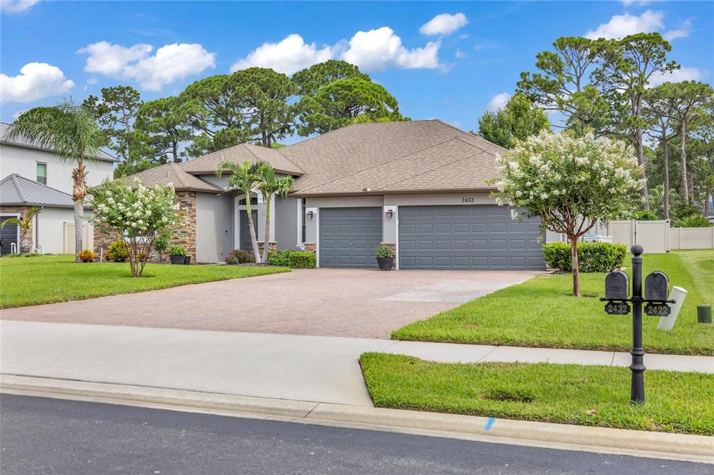 A single-story house with a gray garage, stone accents, and a paved driveway — 2432 OKALANI STREET, MELBOURNE, FL