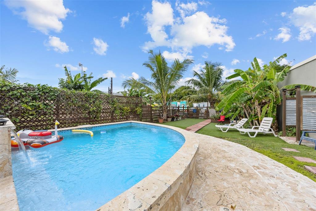 A backyard swimming pool with a stone deck, lounge chairs, and tropical landscaping — Solar 5 CARR 429 BO CALVACHE, RINCON, PR