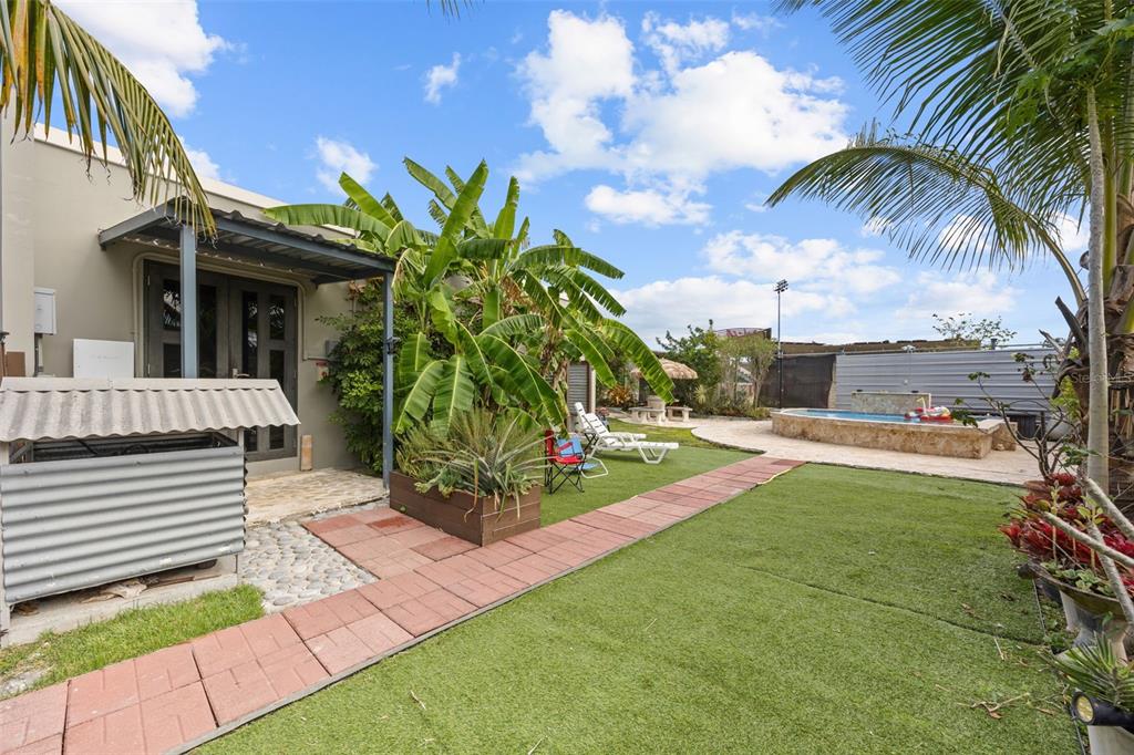 A backyard features a patio, artificial turf, a small pool, and a large banana plant — Solar 5 CARR 429 BO CALVACHE, RINCON, PR