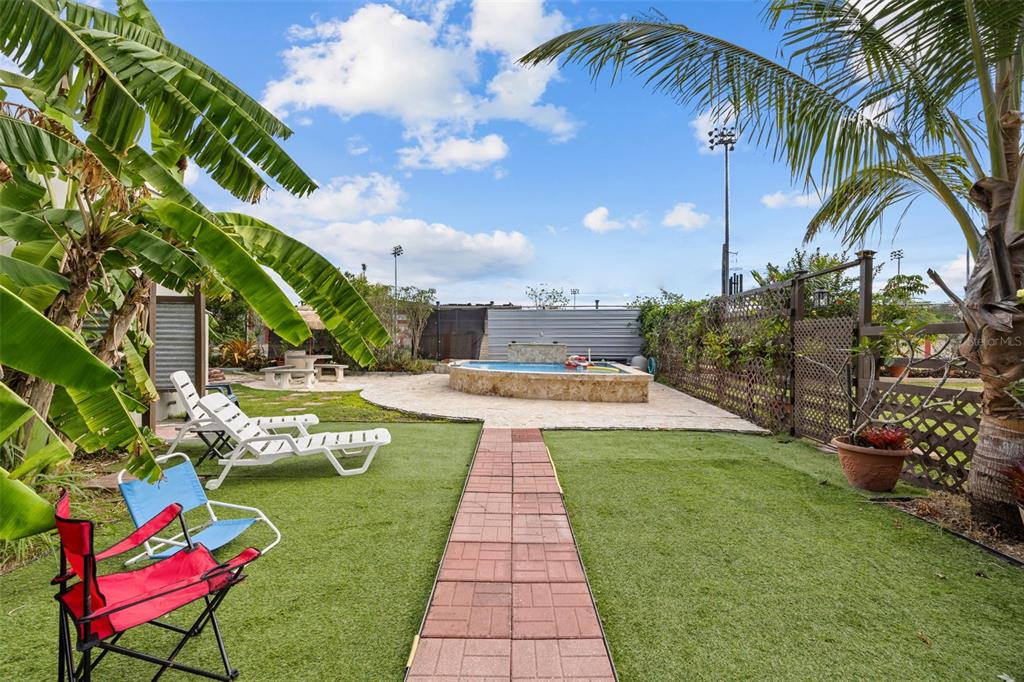 A backyard features a small stone-walled pool, a brick walkway, lounge chairs, and tropical plants — Solar 5 CARR 429 BO CALVACHE, RINCON, PR