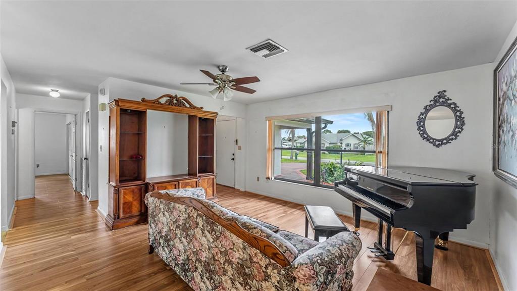 A living room features a floral sofa, a grand piano, and a large wooden entertainment center — 1711 SUNRISE PLACE, SEBRING, FL