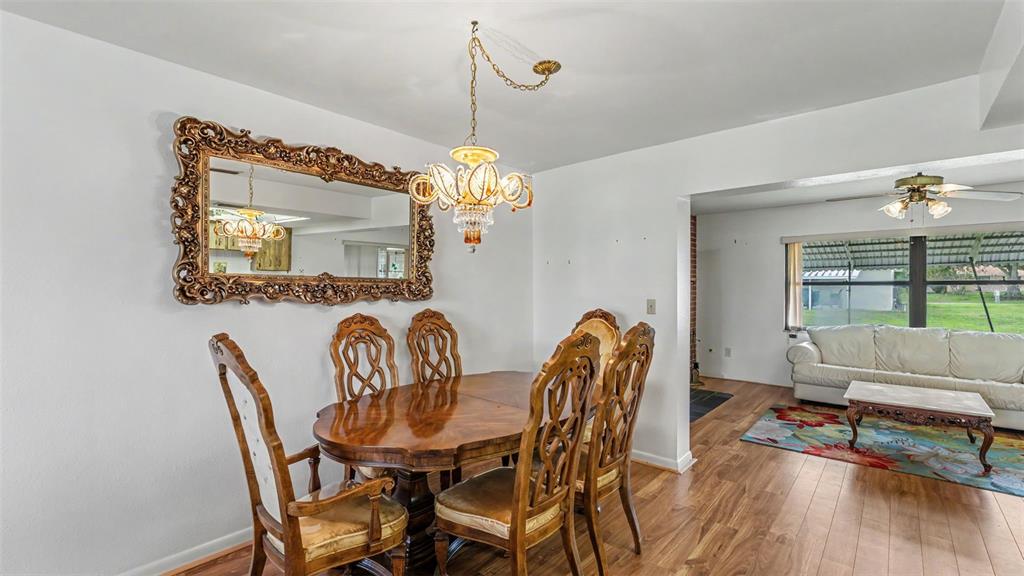 A dining room with a wooden table and chairs sits adjacent to a living area — 1711 SUNRISE PLACE, SEBRING, FL