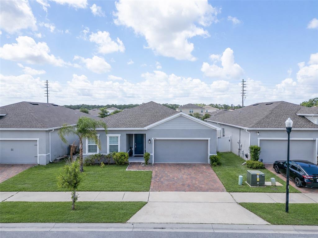 A single-story suburban house with a gray exterior, two-car garage, and a paved driveway — 5542 TOULOUSE LANE, ST CLOUD, FL