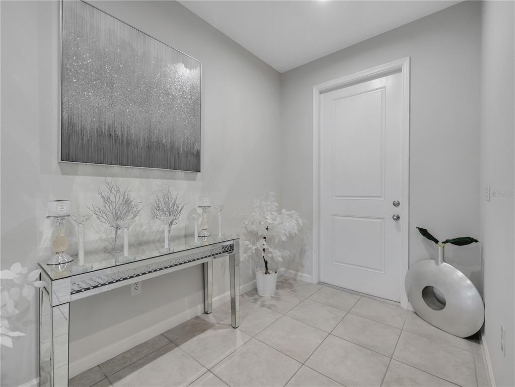 A modern entryway features a mirrored console table, abstract wall art, and light tile flooring — 5542 TOULOUSE LANE, ST CLOUD, FL