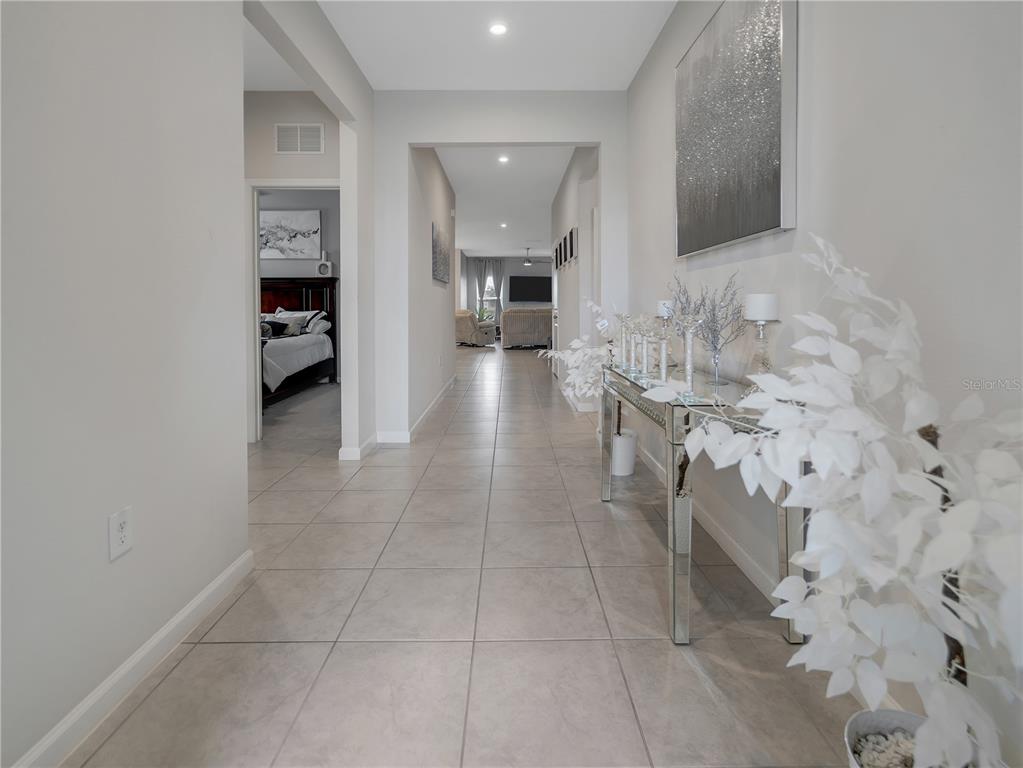 A tiled hallway leads to a living area, featuring a mirrored console table and artwork — 5542 TOULOUSE LANE, ST CLOUD, FL