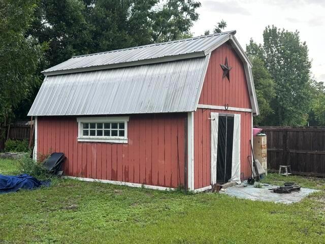 A red wooden barn-style shed with a metal roof stands in a grassy backyard — 444 Quail Street, FL 32159, FL