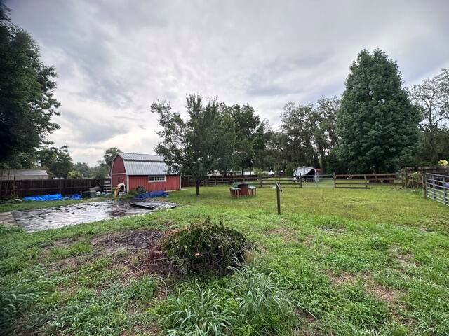 A grassy backyard features a red barn-style shed, a small patio area, and wooden fencing — 444 Quail Street, FL 32159, FL
