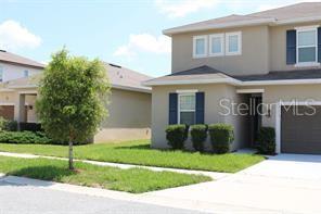 A two-story suburban house with a tan exterior, dark shutters, and a front lawn — 253 ALFORD DRIVE, DAVENPORT, FL
