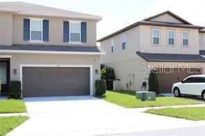 A two-story suburban house with a tan exterior, a two-car garage, and a concrete driveway — 253 ALFORD DRIVE, DAVENPORT, FL