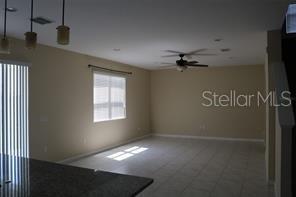 An open-concept living area features tile flooring, a ceiling fan, and a large window — 253 ALFORD DRIVE, DAVENPORT, FL