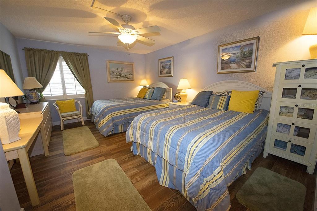 A bedroom features two beds with blue striped bedding, wood-look flooring, and a ceiling fan — 1571 S ATLANTIC AVENUE UNIT 206, NEW SMYRNA BEACH, FL