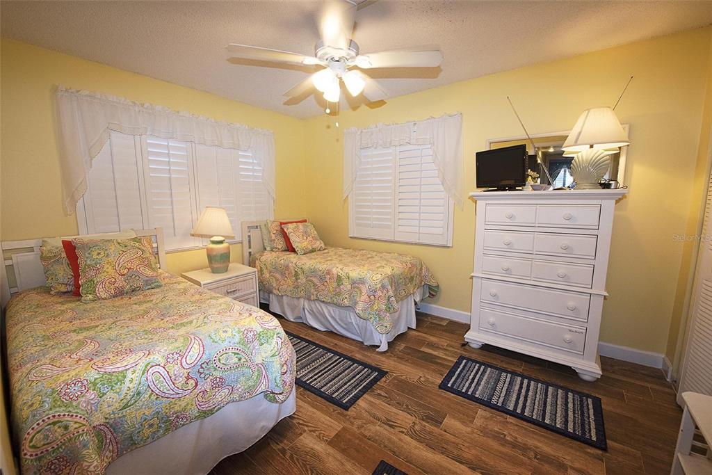 A bedroom with two twin beds, yellow walls, wood-look flooring, and a white dresser — 1571 S ATLANTIC AVENUE UNIT 206, NEW SMYRNA BEACH, FL