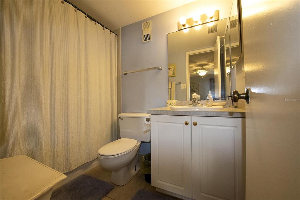A bathroom features a white vanity, a toilet, and a shower with a curtain — 1571 S ATLANTIC AVENUE UNIT 206, NEW SMYRNA BEACH, FL