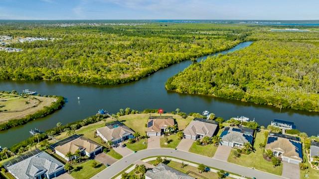 An aerial view of a suburban neighborhood bordering a river and dense forest — 15080 SPANISH POINT DRIVE, PORT CHARLOTTE, FL