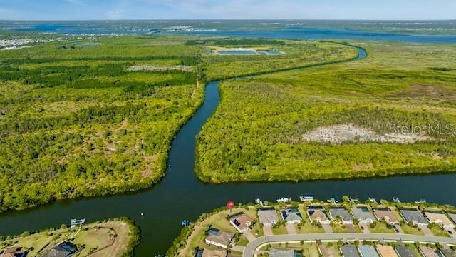 An aerial view shows a residential neighborhood bordering a waterway and expansive green wetlands — 15080 SPANISH POINT DRIVE, PORT CHARLOTTE, FL