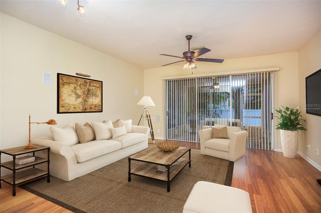 A living room features a beige sofa, armchair, coffee table, and sliding glass doors to a patio — 8471 SANDY BEACH STREET, TAMPA, FL