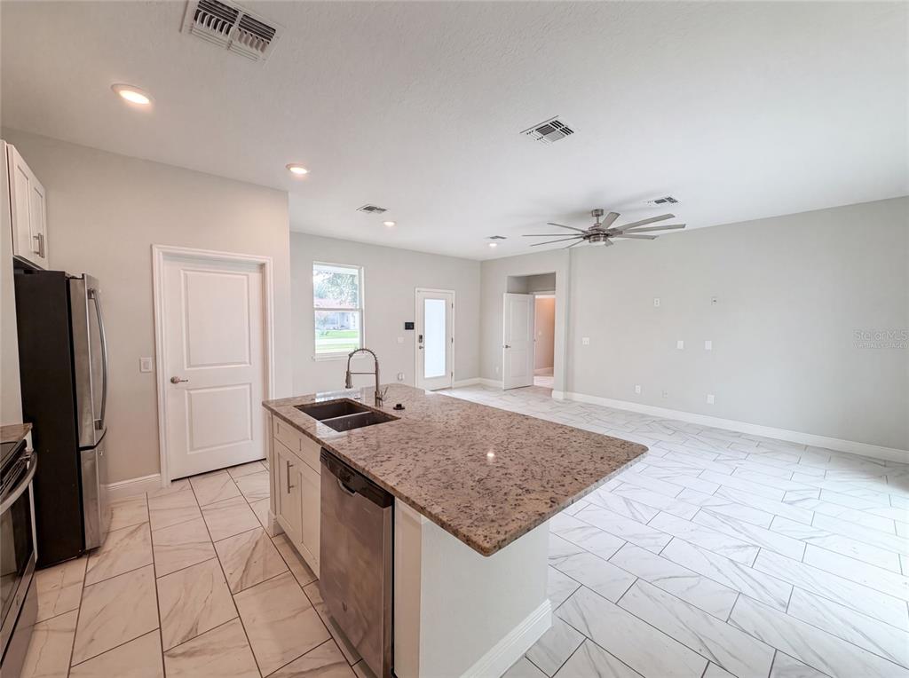 A kitchen with a granite island, stainless steel appliances, and white tile flooring — 1140 BANCROFT STREET, DELTONA, FL