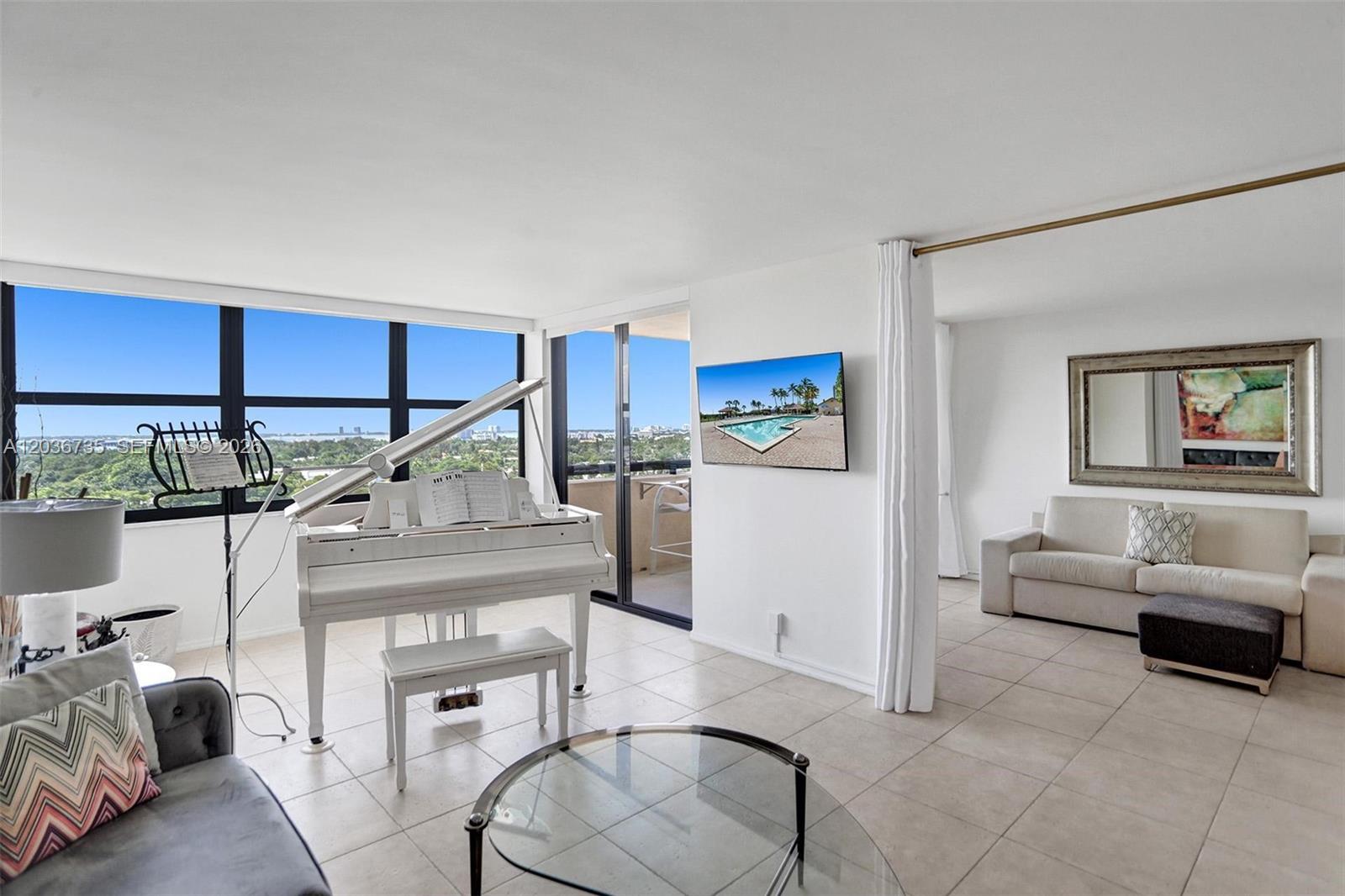 A bright living area features a white grand piano, tile flooring, and a balcony view — 2555 Collins Ave # 1508, Miami Beach FL 33140, MIAMI BEACH, FL