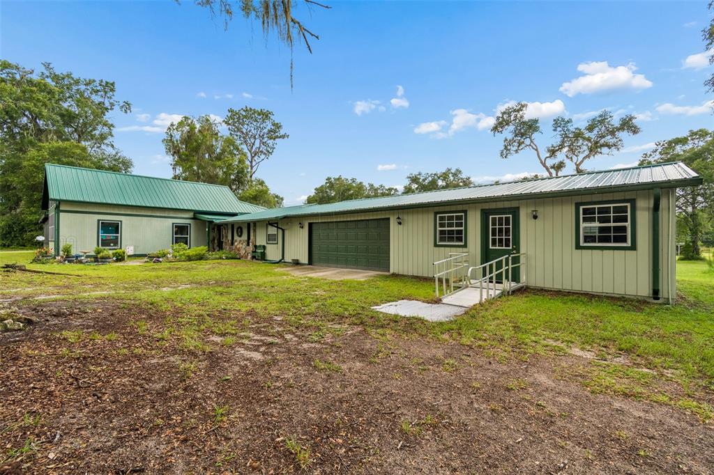 A light green house with a metal roof, a garage, and a wheelchair ramp — 11094 SW 51ST DRIVE, WEBSTER, FL