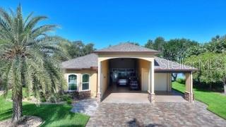 A single-story house with a large covered entryway, a paved driveway, and a palm tree — 492 MEANDERING WAY, POLK CITY, FL