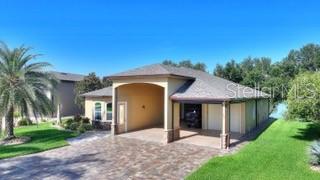 An exterior view of a house with a paved driveway, covered entryway, and attached garage — 492 MEANDERING WAY, POLK CITY, FL