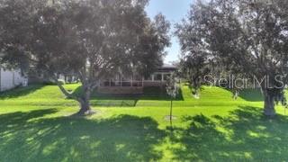 A view of a house exterior with a screened-in porch and large trees on a lawn — 492 MEANDERING WAY, POLK CITY, FL