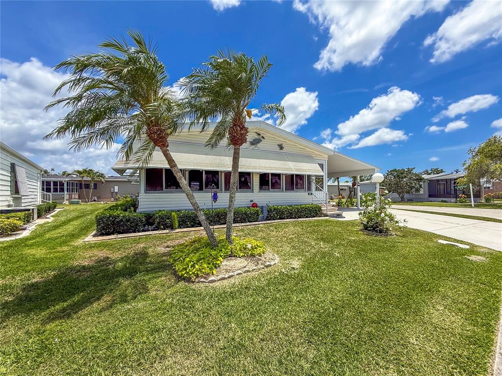 A single-story mobile home with a screened-in porch and two palm trees in the front yard — 73 WHIPPORWILL COURT, ELLENTON, FL